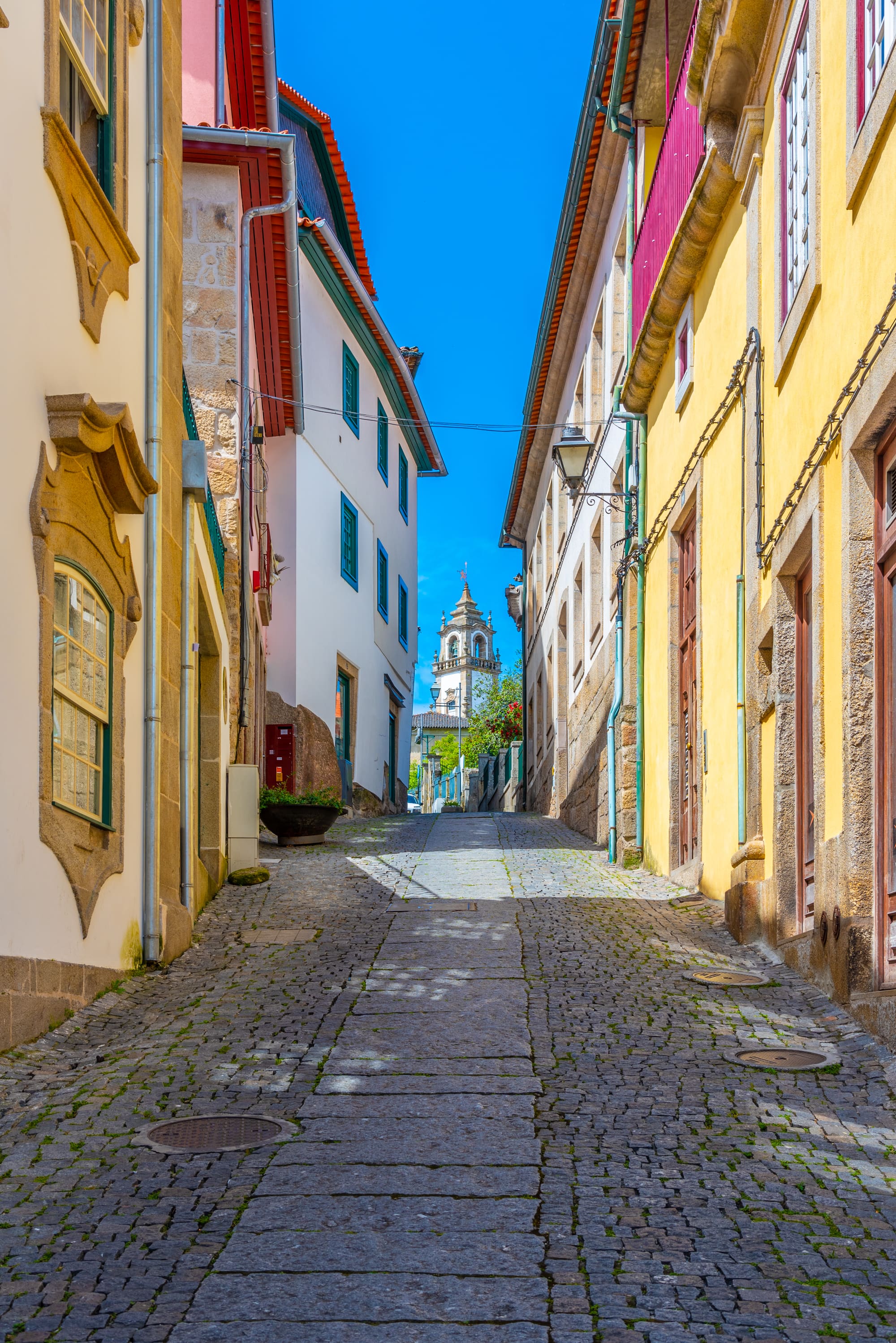 Eine schmale Gasse in der Oberstadt von Viseu mit weißen Häusern und einem Brunnen