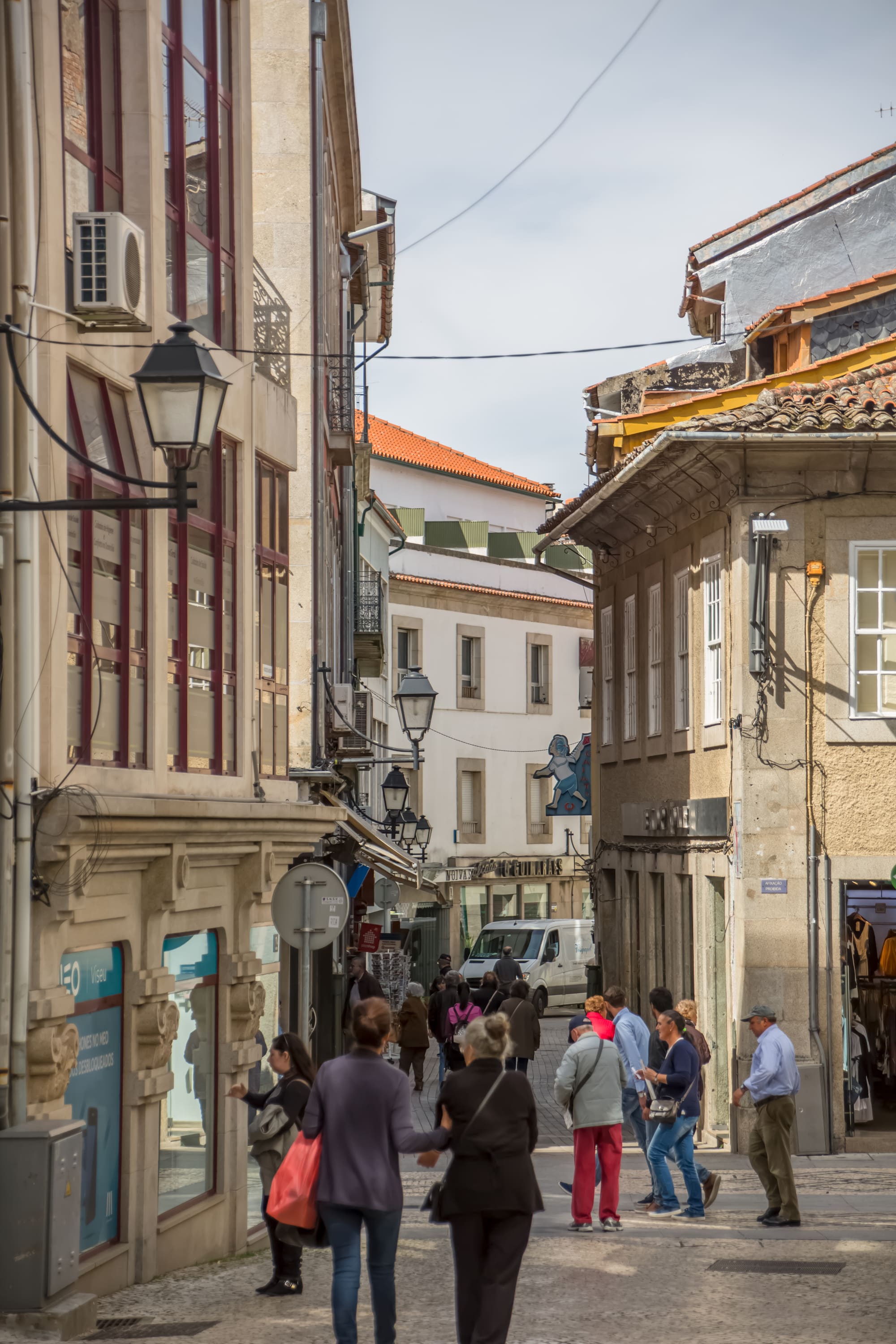 Drukte in een winkelstraat in de binnenstad van Viseu, met klassieke gevels en straatlantaarns
